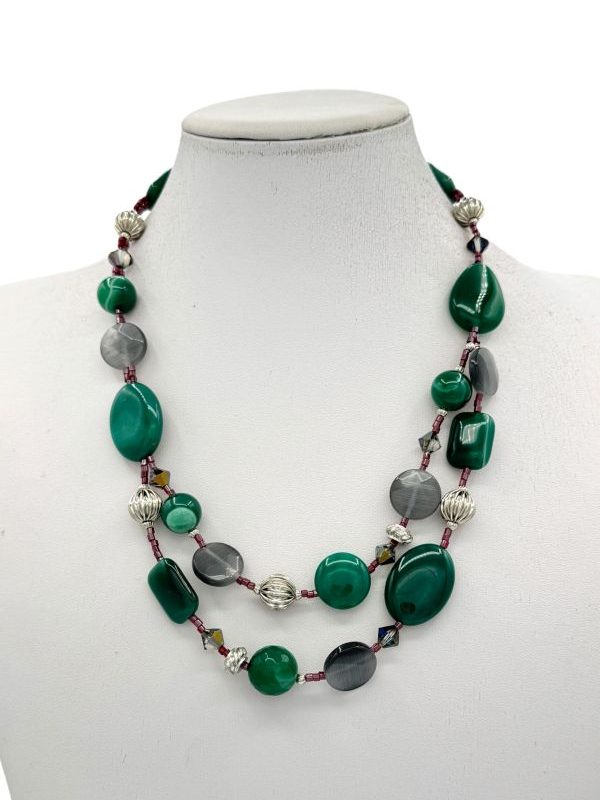 Collana multifilo realizzata con pietre dure di agata verde e occhio di gatto, impreziosita da componenti in alluminio e conteria in vetro rosso brillante. Un gioiello fatto a mano, espressione della nostra maestria artigianale, che unisce eleganza e originalità. Perfetto per aggiungere un tocco di raffinatezza al tuo look. Creato con cura nel nostro laboratorio artigianale a Parma, in Italia. By Ave Caprice