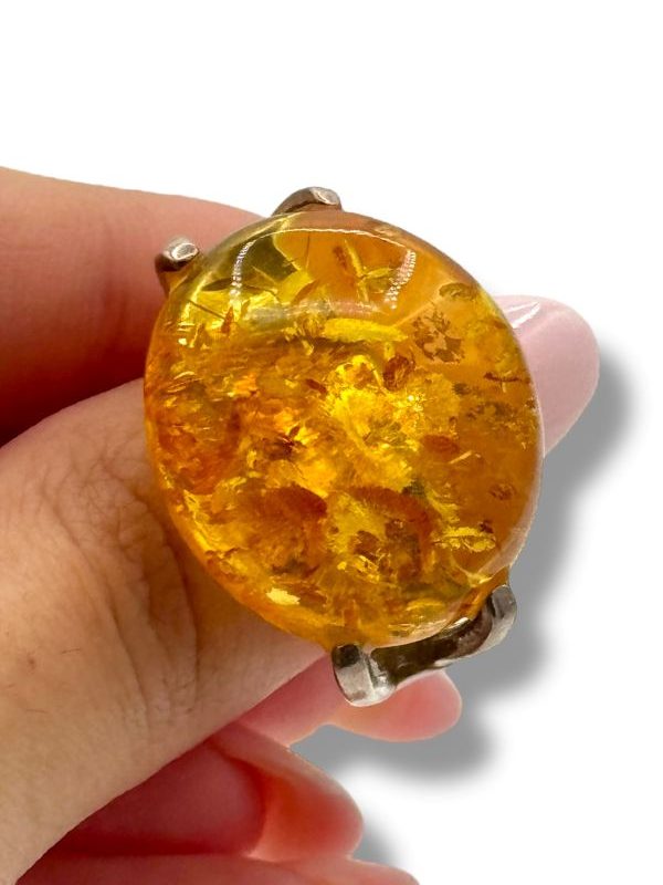 Anello in argento 925 con ambra baltica naturale, dalle inclusioni preziose e riflessi dorati. Un gioiello luminoso e artigianale, dal design elegante e deciso. By Ave Caprice.
