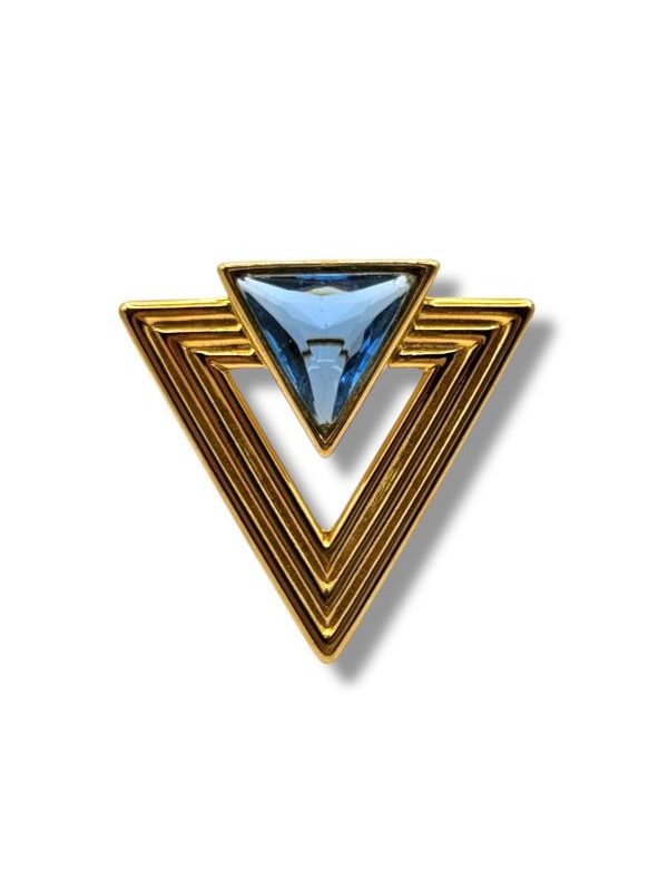 Spilla triangolare in metallo dorato e cristallo azzurro. Pezzo unico Made in Italy, stile moderno e grafico, perfetta su blazer, cappotti e abiti eleganti. By Ave Caprice.