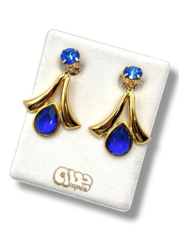 Orecchini pendenti a clip con cristalli blu profondi e metallo dorato lavorato. Design elegante, comfort senza buco, perfetti per serate glamour. By Ave Caprice.